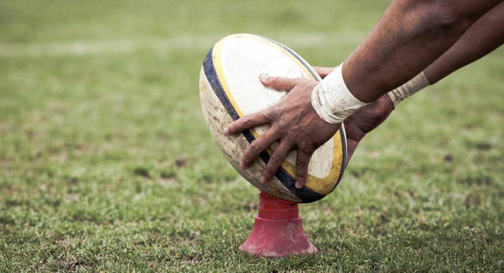 Rugby player placing ball on kicking tee